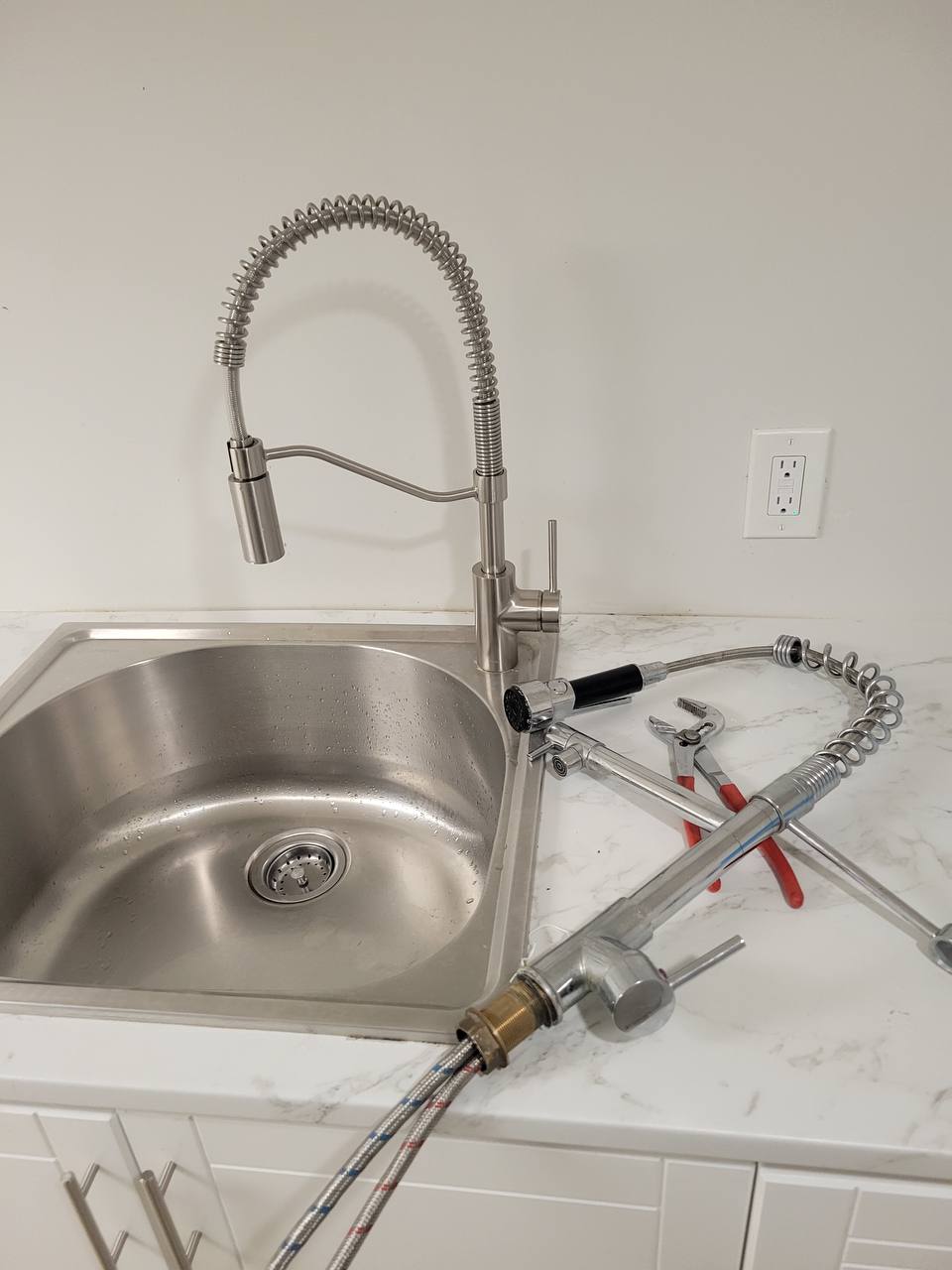 Stainless steel kitchen sink with pull-down sprayer faucet during a sink and faucet repair on a Niagara Region service call