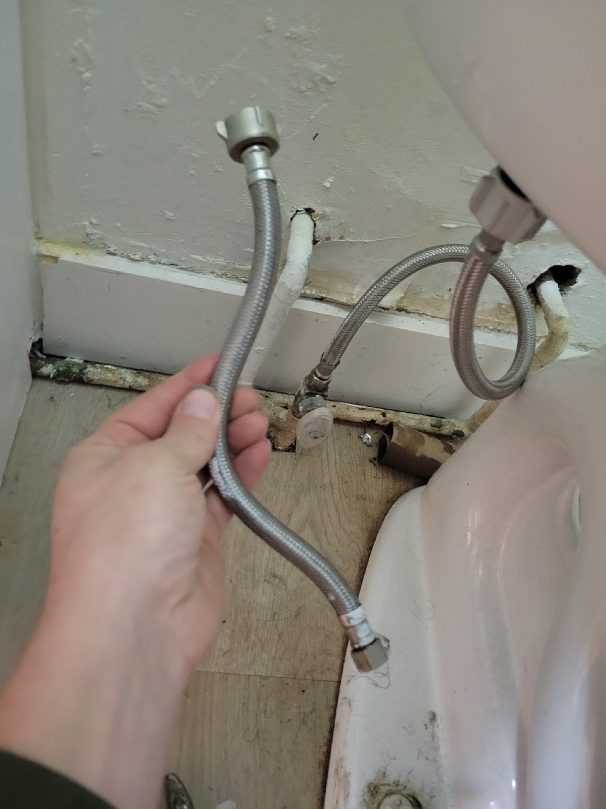 Plumber inspecting a worn toilet supply line during toilet repair in the Niagara Region